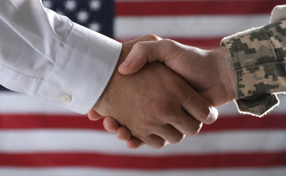 An image depicting a handshake in front of the American flag.